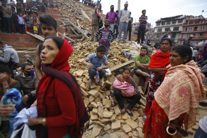 People rest on debris at Durbar Square after an earthquake in Kathmandu, Nepal, Saturday, April 25, 2015. A strong magnitude-7.9 earthquake shook Nepal's capital and the densely populated Kathmandu Valley before noon Saturday, causing extensive damage with toppled walls and collapsed buildings, officials said. AP