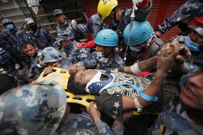 Pemba Tamang is carried on a stretcher after being rescued by Nepalese policemen and U.S. rescue workers from a building that collapsed five days ago in Kathmandu, Nepal, Thursday, April 30, 2015. Crowds cheered Thursday as a Tamang was pulled, dazed and dusty, from the wreckage of a seven-story Kathmandu building that collapsed around him five days ago when an enormous earthquake shook Nepal. (AP Photo/Niranjan Shresta)