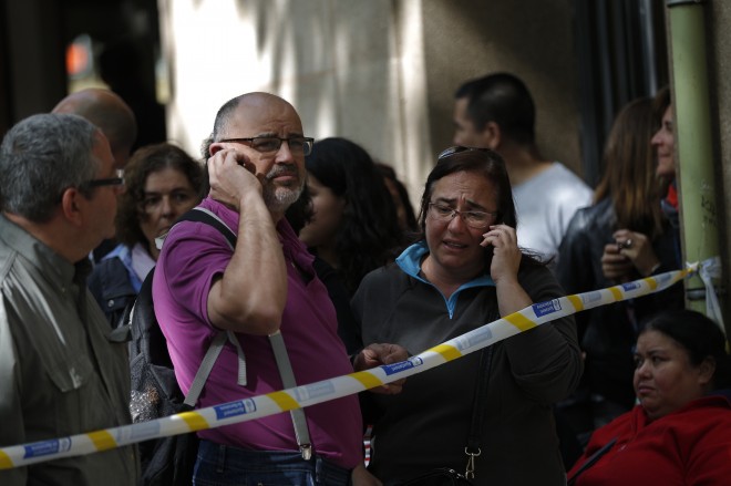 People stand behind a police cordon  outside a school in Barcelona, Spain, Monday, April 20, 2015. A student walked into the Barcelona school Monday morning and killed a teacher and wounded several other high school students on the 16th anniversary of the massacre of students in shootings at Columbine High School in the U.S. state of Colorado. (AP Photo/Emilio Morenatti)