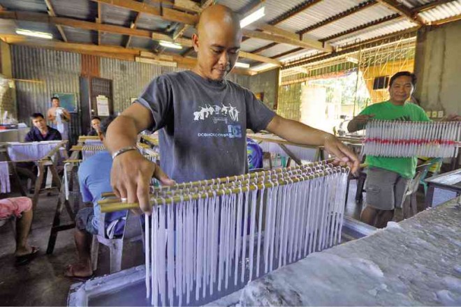 A WORKER dips the wicks hanging on a stick into molten wax until the desired candle weight is attained. WILLIE LOMIBAO/INQUIRER NORTHERN LUZON