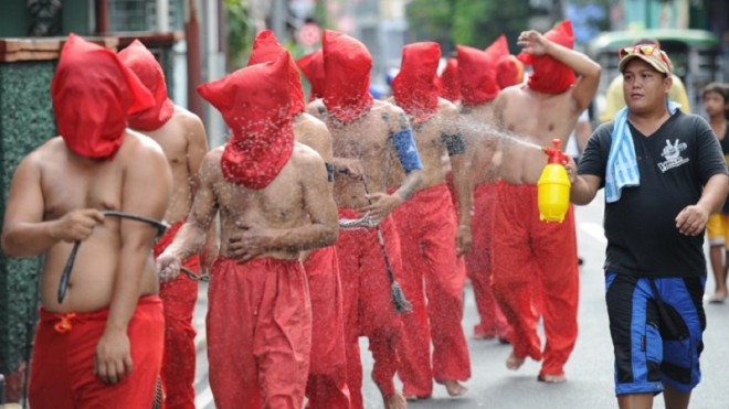 A man (R) sprays penitents with water to cool them down as they flagellate themselves as part of Lenten observance in Manila on April 2, 2015. The dominant Roman Catholic church does not condone flagellation and other extreme acts of penitence including gory Good Friday reenactments of the crucifixion of Jesus Christ, but devout Catholics say it is a means of atoning for their sins and to implore God to spare them and other members of their families from illness or bad luck. AFP PHOTO/TED ALJIBE 
