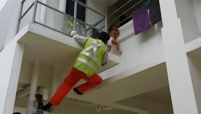 A foreign worker has been hailed a hero after he climbed to the second floor of a Housing Board block at Jurong East Street 32 to save a toddler whose head was stuck between the railings. -- PHOTO: SCREENGRAB FROM VIDEO/ALVIN LIM 