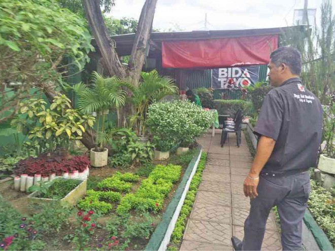 WORKERS process biodegradable waste to make organic fertilizer while at right, Fort Bonifacio barangay captain Alan Oliman shows off the herbal and medicinal plants at the MRF garden.