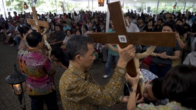 Minority Indonesian Catholics kiss the cross during a Good Friday mass at the Jakarta cathedral on April 3, 2015, as Christian devotees mark holy week in Indonesia, a predominantly Islamic nation.   AFP PHOTO / ROMEO GACAD