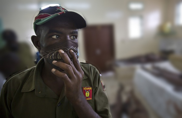 A hospital security guard covers his mouth and nose due to the smell as he views the bodies of the alleged attackers laid out on the slab and floor, in the hospital mortuary in Garissa, Kenya Saturday, April 4, 2015. Later authorities displayed the bodies of the alleged attackers involved in the killings at Garissa University College on the bed of a pickup truck that drove slowly past the crowd gathered in a large open area. AP