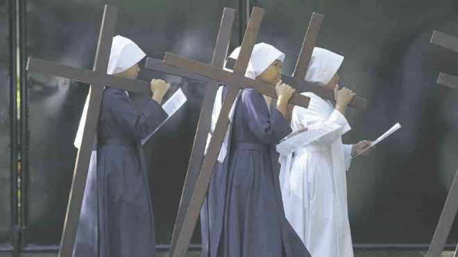 NUNS AND CROSSES Nuns carry wooden crosses as they make the Stations of the Cross at the Philippine Center of St. Pio of Pietrelcina in Quezon City. AP