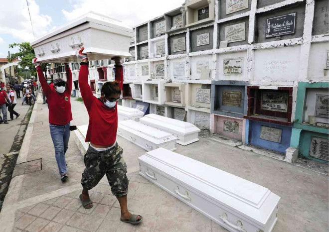 NAMELESS DEAD  Workers carry coffins of the still-unidentified victims of the Valenzuela City fire for temporary interment at Arkong Bato cemetery on Friday. The factory disaster provided a new rallying cry for militant labor groups who used the workers’ products—slippers—to express their condolences and indignation. PHOTOS BY RAFFY LERMA 