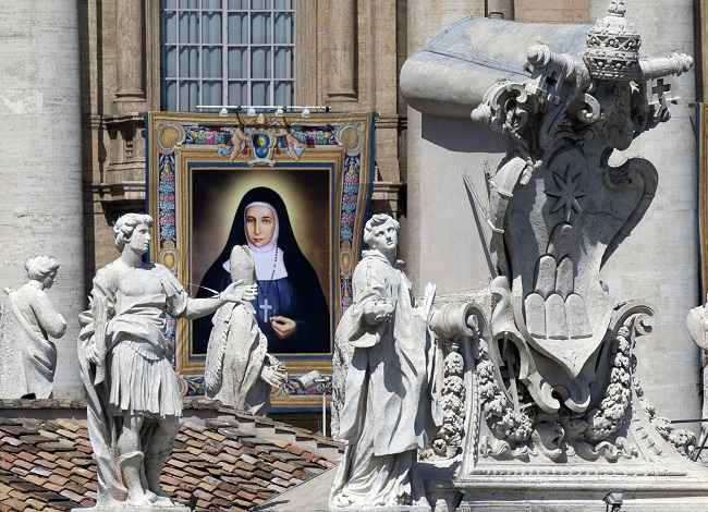 A tapestry showing St. Marie Alphonsine Ghattas hangs from a balcony of St. Peter's Basilica at the Vatican, Sunday, May 17, 2015. Pope Francis canonized two nuns from what was 19th century Palestine on Sunday in hopes of encouraging Christians across the Middle East who are facing a wave of persecution from Islamic extremists. Sisters Mariam Bawardy and Marie Alphonsine Ghattas were among four sisters who were made saints Sunday at a Mass in a sun-soaked St. Peter's Square. AP