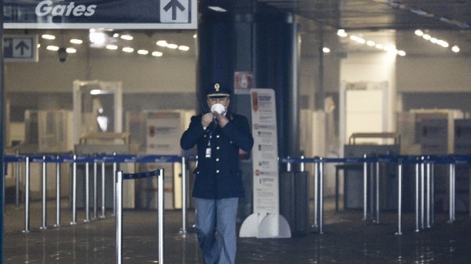 A police officer wears a protective mask as he walks inside Rome's Fiumicino airport main international terminal after a fire broke out overnight, Thursday, May 7, 2015. Italy's flagship Alitalia airline said in a statement that all departures have been canceled up to 2 p.m. (1200 GMT) and that only intercontinental flights will be allowed to land during that period. The fire, which broke out after midnight, involved about 400 square meters (more than 4,000 square feet) of retail space. No cause was immediately identified. (AP Photo/Alessandra Tarantino)