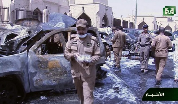 In this still image taken from video provided by Saudi TV, burnt out cars are seen as investigators collect evidence, in the aftermath of a suicide bomb outside the the Imam Hussein mosque in the port city of Dammam, Saudi Arabia, Friday, May 29, 2015.  A suicide bomber blew himself up in the parking lot of a Shiite mosque in eastern Saudi Arabia during Friday prayers, killing four people in the second such attack in as many weeks claimed by the Islamic State group. (Saudi Television via AP) SAUDI ARABIA OUT
