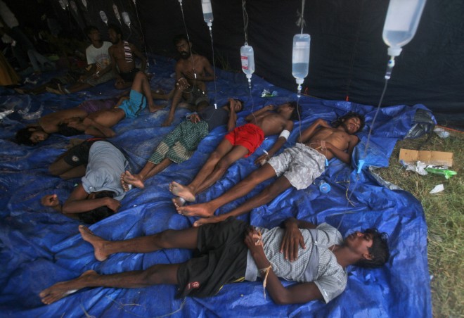Newly arrived migrants receive medical treatment under a makeshift tent at Kuala Langsa Port in Langsa, Aceh province, Indonesia, Friday, May 15, 2015. More than 1,000 Bangladeshi and ethnic Rohingya migrants came ashore in different parts of Indonesia and Thailand on Friday, becoming the latest refugees to slip into Southeast Asian countries that have made it clear the boat people are not welcome. (AP Photo/Binsar Bakkara)