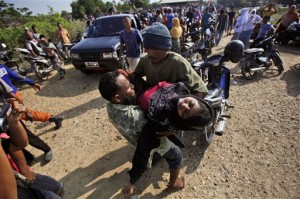 Acehnese men help an unconscious migrant woman upon her arrival in Simpang Tiga, Aceh province, Indonesia Wednesday, May 20, 2015. In a potential breakthrough in Southeast Asia's humanitarian crisis, Indonesia and Malaysia offered Wednesday to provide temporary shelter to thousands of migrants stranded at sea after weeks of saying they weren't welcome.  AP PHOTO/BINSAR BAKKARA