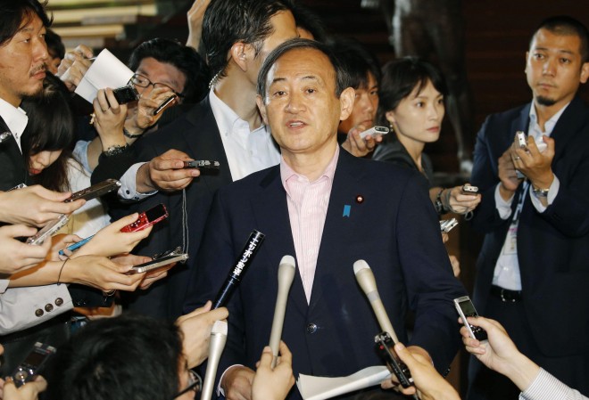 Japan's Chief Cabinet Secretary Yoshihide Suga, center, answers a reporter's question on an eruption of a volcano in southern Japan, at prime minister's official residence in Tokyo Friday, May 29, 2015. Mount Shindake on Kuchinoerabu island erupted in spectacular fashion on Friday, spewing towering black-gray clouds into the sky. Authorities ordered residents to evacuate the island. (Kyodo News via AP) 
