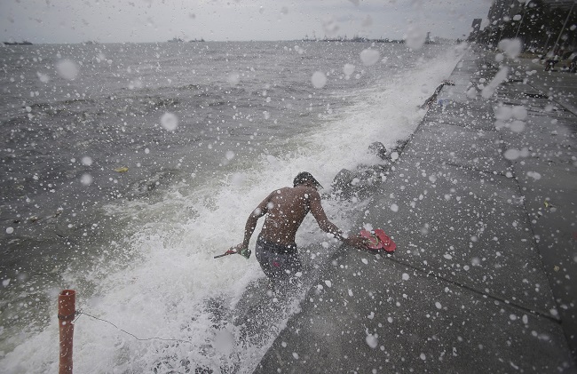 Strong waves hit a Filipino man as he retrieves rubber slippers along Manila bay, Philippines on Sunday, May 10, 2015. A powerful typhoon slammed into the northeastern tip of the Philippines on Sunday, as about 2,500 residents in two provinces huddled in shelters following warnings by officials to evacuate coastal and mountainous villages. AP