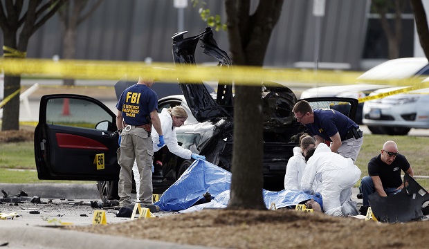 FBI crime scene investigators document the area around two deceased gunmen and their vehicle outside the Curtis Culwell Center in Garland, Texas, Monday, May 4, 2015. Police shot and killed the men after they opened fire on a security officer outside the suburban Dallas venue, which was hosting provocative contest for Prophet Muhammad cartoons Sunday night. (AP Photo/Brandon Wade)