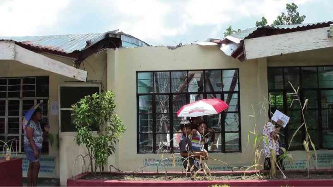 NOT YET REPAIRED Visitors of Albay Central Elementary School in Legazpi City pass by one of the classrooms damaged by Typhoon “Glenda” last year. MICHAEL B. JAUCIAN/INQUIRER SOUTHERN LUZON