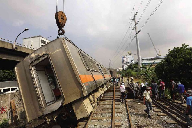 PNR workers get back on track the two train coaches derailed in Wednesday’s accident in Taguig City. According to the PNR, the derailment may have been caused by the theft of rail track parts.  JOAN BONDOC 