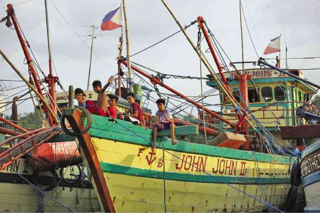 IDLE BOATS  Children play on a fishing boat docked in Sitio Balogo, Barangay (village)  Inhobol, Masinloc, Zambales province, which faces the West Philippine Sea. The fishermen say they have been avoiding the Scarborough Shoal due to the aggression of Chinese Coast Guard vessels. INQUIRER PHOTO/JOAN BONDOC