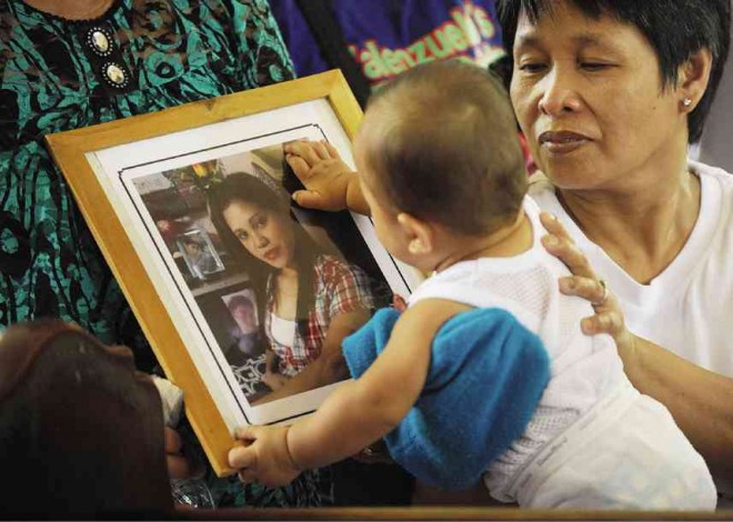  A CHILD touches the picture of his mother, one of the factory workers killed in the May 13 Kentex fire in Valenzuela City, during a special Mass held for the victims over the weekend. Of the 72 victims, 69 have yet to be identified as their bodies were burned beyond recognition. AFP FILE PHOTO 