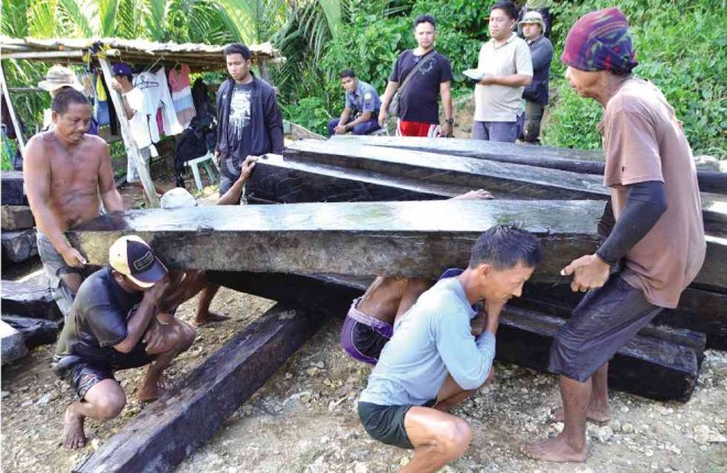 DENR agents and policemen carry some of the flitches found at the bottom of a river in Mauban town in Quezon province. PHOTO FROM DENR