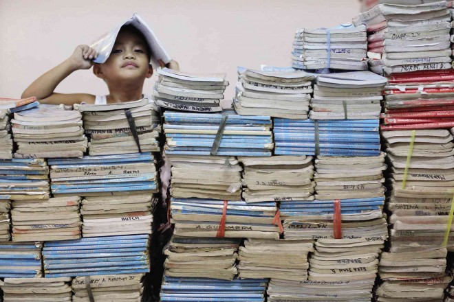 GETTING READY  Grade schooler Robby Zamora looks over a mountain of textbooks at  Commonwealth Elementary School in Quezon City as he tries to help his father, a teacher and property custodian in the school, prepare for Monday’s reopening of classes. Robby is  one of  millions of children going to school for the first time under the government’s K to 12 education program. JOAN BONDOC