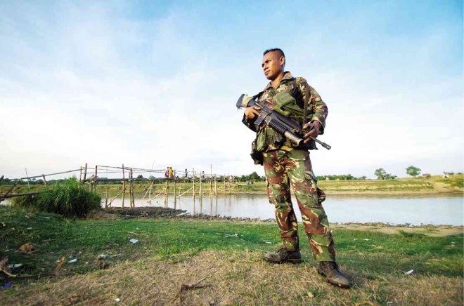 A SOLDIER is stationed near a bullet-riddled wooden bridge in the village of Tukanalipao in Mamasapano town, Maguindanao province, in this photo taken weeks before Social Welfare Secretary Corazon Soliman came to distribute cash to the impoverished community. RICHARD BALONGLONG/INQUIRER NORTHERN LUZON