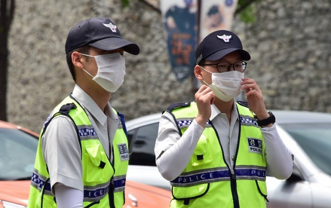 South Korean policemen wearing face masks walk on a street in downtown Seoul on June 19. South Korea has said that the MERS outbreak that has killed 24 people appears to have begun subsiding, as it reported one new case—the lowest rate of new infections in two weeks. AFP