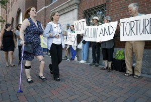 Boston Marathon bombing victim Erika Brannock, foreground left, and her mother Carol Downing, foreground right, walk past demonstrators outside federal court in Boston, Wednesday, June 24, 2015. AP