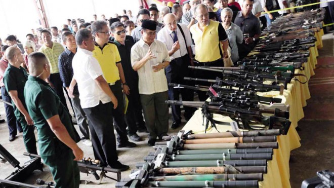 REBEL ARMS  Guns of different types are laid out on the table after they were “decommissioned” by the MILF in Sultan Kudarat, Maguindanao province. Witnessing the handover are President Aquino, MILF chair Murad Ebrahim, Interior Secretary Mar Roxas and Presidential Peace Adviser Teresita Deles.  GRIG C. MONTEGRANDE