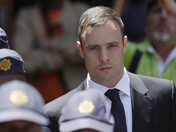 FILE - In this Friday, Oct. 17, 2014 file photo, Oscar Pistorius is escorted by police officers as he leaves the high court in Pretoria, South Africa. Prison officials have recommended that Pistorius be released from prison on Aug. 21 to go under house arrest. Acting National Commissioner of Correctional Services Zach Modise says that a prison committee recommended Pistorius be released  after serving one sixth of his five-year sentence, or 10 months, for shooting girlfriend Reeva Steenkamp. A decision by the parole board is pending. (AP Photo/Themba Hadebe, File)