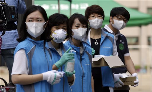 South Korean health workers from a community health center wearing masks as a precaution against MERS, Middle East Respiratory Syndrome, virus, wait to check examinees' temperature and to sanitzie their hands at a test site for a civil service examination in Seoul, South Korea, Saturday, June 13, 2015.  AP