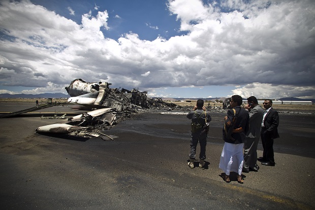 FILE - In this Tuesday, May 5, 2015 file photo, airport officials look at the wreckage of a military transport aircraft destroyed by Saudi-led airstrikes, at the Sanaa International airport, in Yemen. A Saudi-led coalition continues to bomb Shiite rebels also known as Houthis and allied forces across the country. The airstrikes campaign, which began on March 26, and the ground fighting have killed hundreds and displaced at least 300,000 Yemenis.  (AP Photo/Hani Mohammed, File)