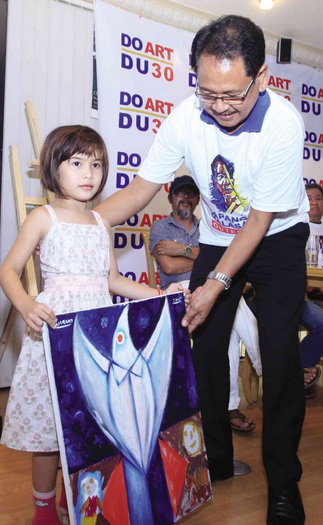 A YOUNG ARTIST from Bacolod City hands over her work to an official of a group of artists supporting a campaign to push Davao City Mayor Rodrigo Duterte to run for President next year. TONEE DESPOJO/CEBU DAILY NEWS