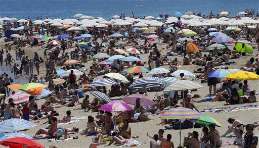 People sunbathe on a beach in Barcelona, Spain, Sunday, June 28, 2015. Weather stations across Spain are warning people to take extra precautions as a heat wave engulfs much of the country, increasing the risk of wildfires. The country's meteorological agency says a mass of hot air originating in Africa is moving northwards, bringing with it until at least Monday temperatures reaching 40 C (104 F). AP