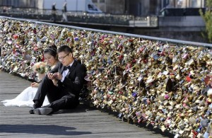 This April 16, 2014 file photo shows a newly wed couple resting on the Pont des Arts in Paris, France, with 'love locks' clinging to the bridge as background. AP Photo