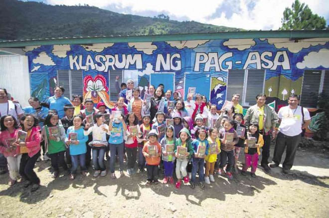 STUDENTS of Lebeng Primary School in Sitio Lebeng, Barangay Bashoy, Kabayan in Benguet province, together with  DepEd Undersecretary of Partnerships and External Linkages Mario A. Deriquito (in blue shirt) and  Angelo Valencia (wearing sunglasses at the right side) of “Klasrum ng Pag-asa,” raise their learners’ kits donated by private companies during the DepEd Brigada Eskwela 2015. Richard Balonglong/INQUIRER NORTHERN LUZON