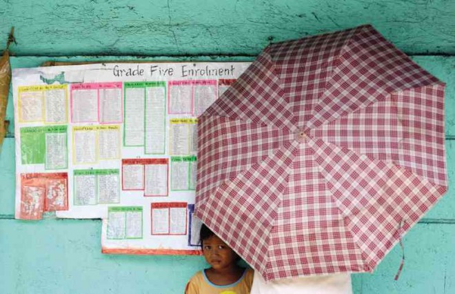 A GIRL peeks out from under the umbrella of her mother who is checking out of the list of qualified enrollees at the H. J. Atienza Elementary School in Baseco Compound, Tondo, Manila on Sunday, a day before the start of classes. NIÑO JESUS ORBETA