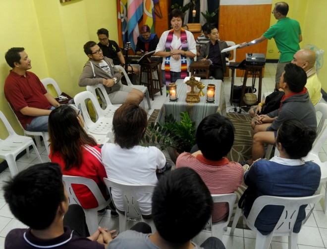 In this photo taken on July 5, 2015 pastor Kakay Pamaran (C) preaches the gospel in a Lesbian, Gay, Bisexual, and Transgender (LGBT) church in Manila.  A gospel serenade of deep baritones echoed through a dim alley in one of the Philippine capital's red light districts one humid Sunday evening -- the joyful sounds emanating from a tiny religious outpost for homosexuals.     AFP PHOTO / Jay DIRECTO