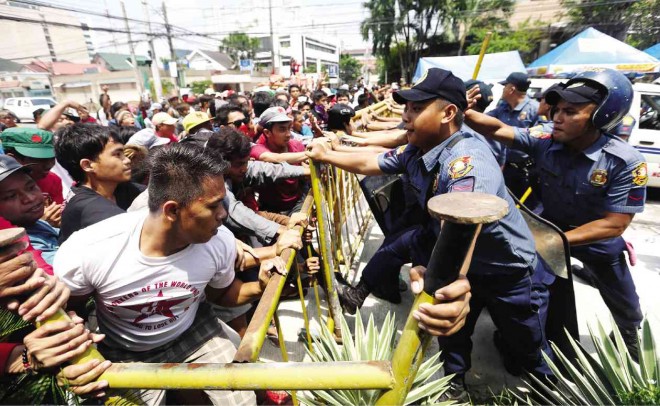 PRE-SONA SCUFFLE  Militants belonging to Bagong Alyansang Makabayan and other groups try to get past metal barriers put up by policemen during a protest on Times Street in Quezon City, where President Aquino’s residence is located, on the eve of his final State of the Nation Address.  LYN RILLON