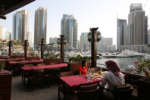 In this April 1, 2015 photo, people dine at the Reem al-Bawadi restaurant  at the Marina Waterfront in Dubai, United Arab Emirates. Dubai Marina is finally coming into its own after years of seemingly endless construction work. Hewn out of the desert and connected to the Persian Gulf by channels at each end, the 3.5 kilometer (2.2 mile) U-shaped canal would be an engineering marvel even without its skyline. An eatery-lined walkway winding along the canal provides plenty of chances to gawk at the high-end yachts on display.  (AP Photo/Kamran Jebreili)