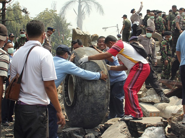 Military personnel remove an aircraft wheel at the site where an air force cargo plane crashed in Medan, North Sumatra, Indonesia, Tuesday, June 30, 2015. An Indonesian air force Hercules C-130 plane with 12 crew aboard has crashed into a residential neighborhood in the country's third-largest city Medan. (AP Photo/Dedy Zulkifli)