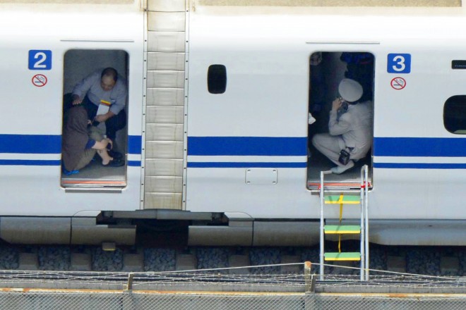 In this June 30 photo, a passenger, left, crouches inside a train car of a bullet train which made an emergency stop after a man set himself on fire, in Odawara, west of Tokyo. AP