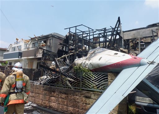 The wreckage of a plane is seen at a crash site in the suburbs of Tokyo, Sunday, July 26, 2015. At least three people died, while three people were pulled alive from the wreckage, officials said.  KYODO NEWS VIA AP 