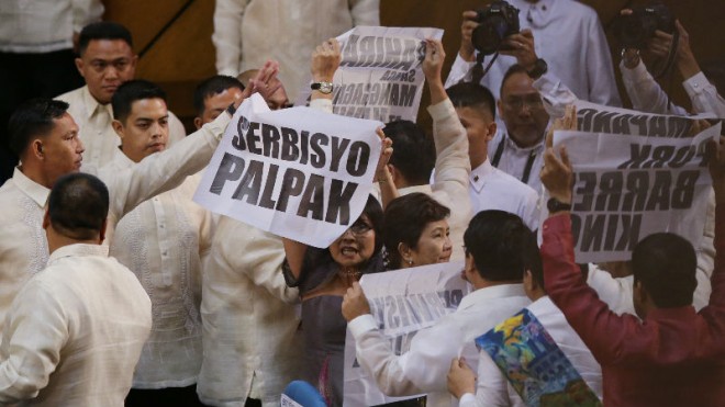 Left wing members of Congress hold up signs including one that says "Poor Service" as Presidential Security tries to stop them after the last State of the Nation Address of Philippine President Benigno Aquino III at the joint session of the 16th Congress at the House of Representatives in suburban Quezon city, north of Manila, Philippines on Monday, July 27, 2015. (AP Photo/Aaron Favila)