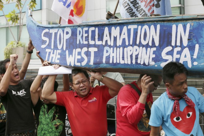 In this July 3, 2015, file photo, protesters carry a boat painted with slogans during a rally outside the Chinese Consulate at the financial district of Makati city, east of Manila, Philippines, to protest China's reclamations of disputed islands off South China Sea. China is standing pat on its decision to reject arbitration by an international tribunal that will begin formal hearings this week to resolve a long-seething feud with the Philippines over the South China Sea, Beijing's ambassador to Manila said Monday, July 6, 2015. (AP Photo/Bullit Marquez)