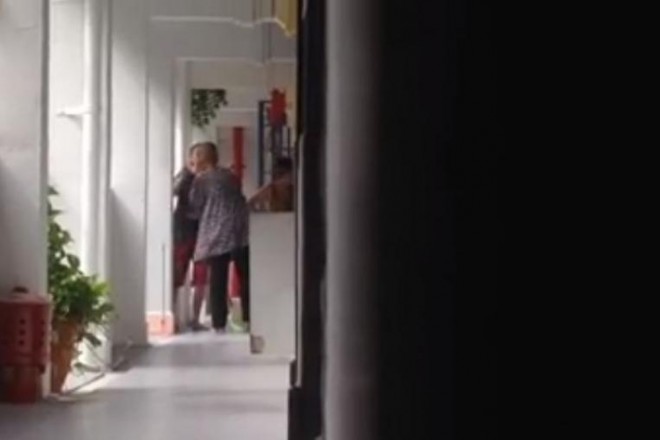 The elderly woman receiving a slap from one of the two watching women outside a HDB flat at Lower Delta Road. PHOTO: SCREENGRAB FROM FACEBOOK VIDEO