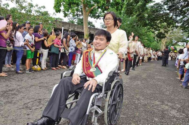 PUSHED by his mother Mayette, Carl Adrian Castueras wears a big smile and his “sablay” as he rolls down the graduation grounds at the University of the Philippines in Los Baños, Laguna province. Despite his condition, Castueras finished his Bachelor of Science in Computer Science course a cum laude. OLYMPUS LAFORTEZA/CONTRIBUTOR