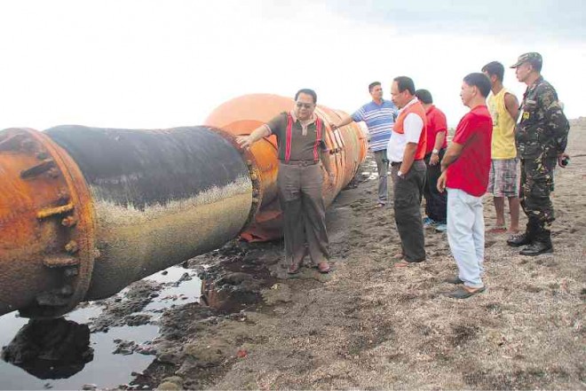 SAFETY ISSUE Zambales Gov. Hermogenes Ebdane Jr. inspects a portion of a floater assembly, a device used in dredging operations, that was found in the province’s waters last week. The assembly is kept in Barangay San Agustin in Iba town. CONTRIBUTED PHOTO 