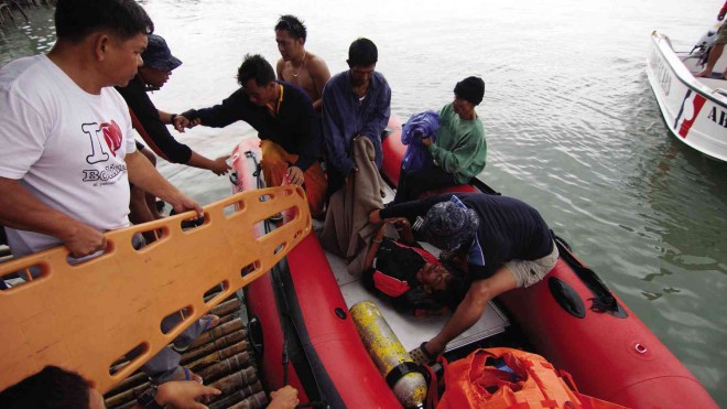 PHILIPPINE Coast Guard personnel attend to one of the rescued fishermen in the West Philippine Sea as they arrive in Sual, Pangasinan province. BUDANG NISPEROS / INQUIRER NORTHERN LUZON