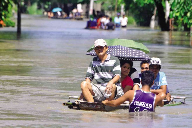 RESIDENTS of Barangay Lasip in Calasiao, Pangasinan province, take a boat ride from their houses to the town center as flood waters from the swollen Marusay River continue to submerge their village. WILLIE LOMIBAO / INQUIRER NORTHERN LUZON